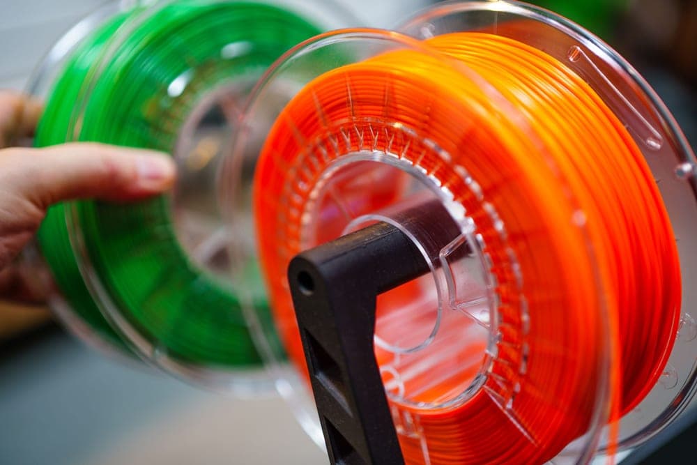 Spools of 3D printer filament stacked on a shelf - a stand-in for the Overture PLA, not a photograph of this model