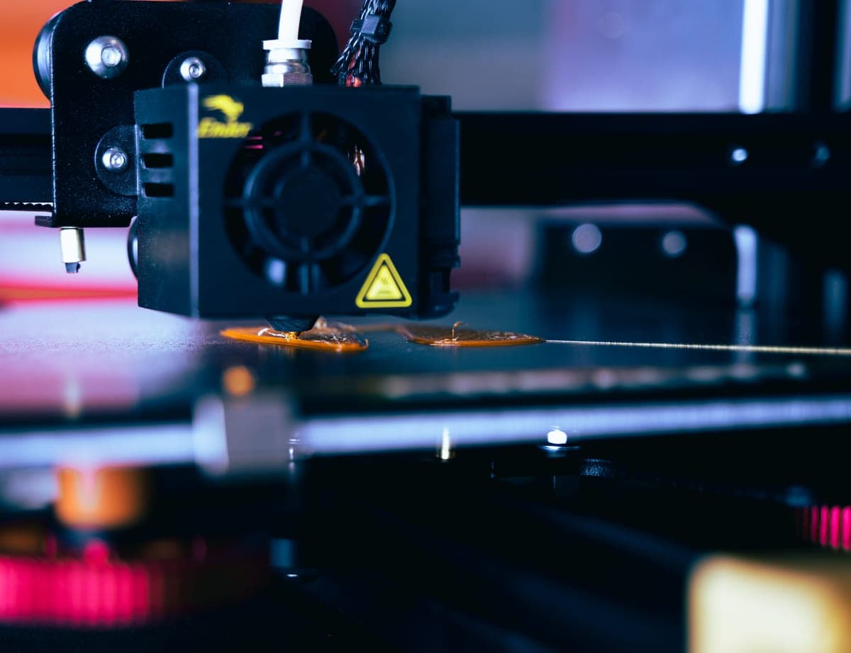 A desktop 3D printer part-way through a print, lit against a dark background