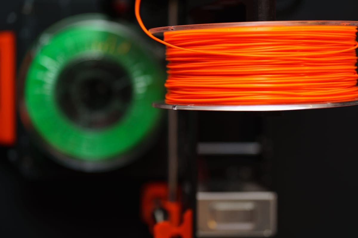 Several spools of PLA filament in different colors arranged on a dark surface