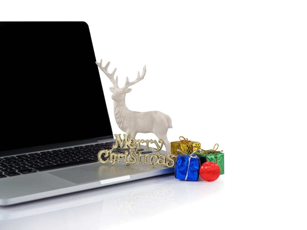 A small figurine sitting on a laptop, wrapped for the holidays