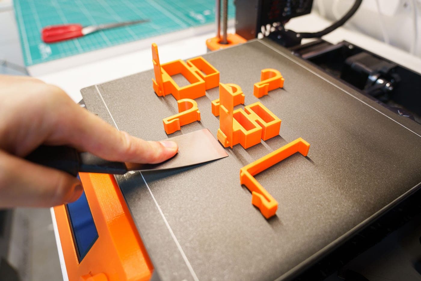 A hand reaching over a 3D printer while it prints