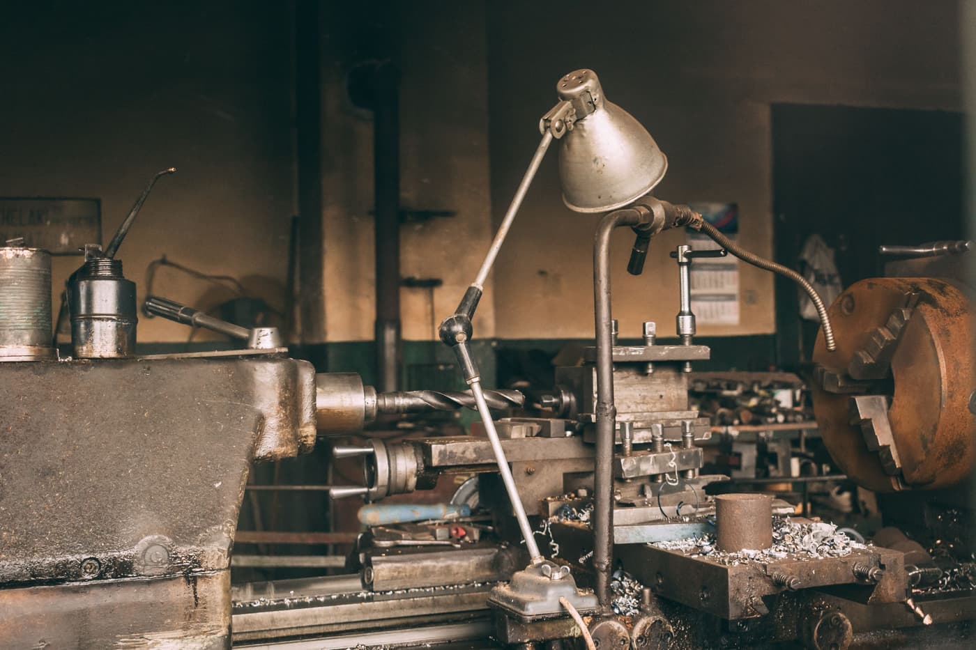 A workbench with a 3D printer beside other workshop machinery in low light
